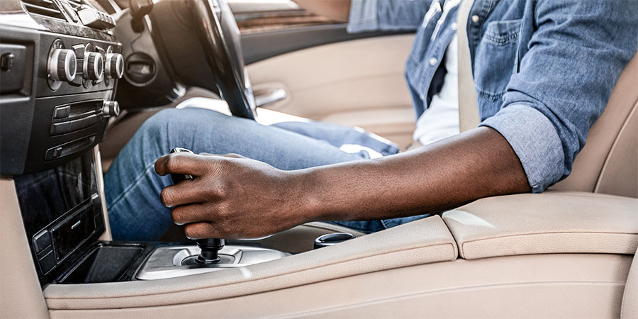 Close up of driver shifting gear in a BMW with tan leather interior