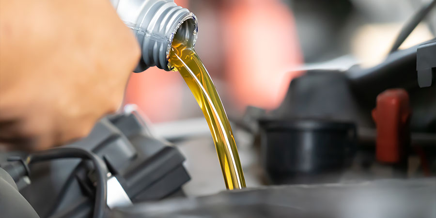 Close up of BMW service technician pouring oil into engine